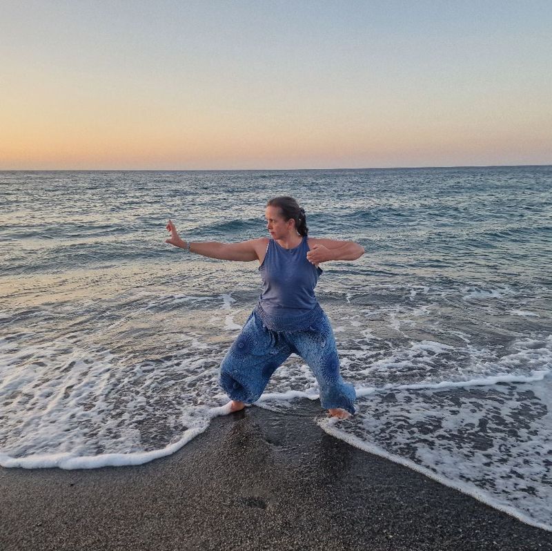 Jude practising qigong at the water's edge at sunset